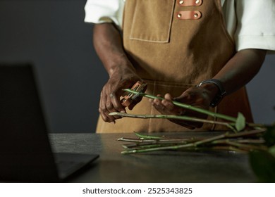 Minimal closeup of male florist arranging bouquet and cutting flower stems in low lighting copy space - Powered by Shutterstock