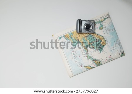 Minimal composition of camera and map on white background with copy space.