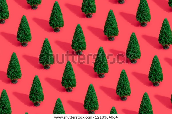 Minimal composition pattern background of green Christmas trees on pastel red. New Year concept.