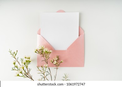 Minimal composition with a pink envelope, white blank card and a wax flower on a white background. Mockup with envelope and blank card. Flat lay. Top view. - Shutterstock ID 1061972747