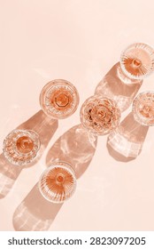 Minimal composition Top view glasses of rose wine or champagne on pink background, artistic shadows and sun glare. Aesthetic still life crystal wineglass, sparkling drinks for summer party, copyspace