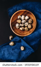 Minimal concept of fresh quail eggs in the wooden bowl on the dark background with blue saten or silk around. - Shutterstock ID 1931934119