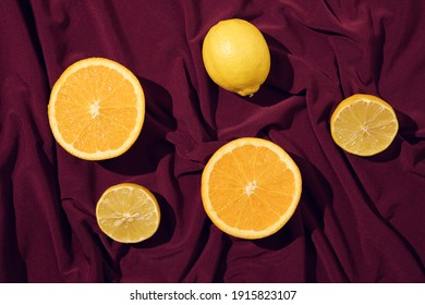 Minimal concept of orange slice and lemon on a beautiful dark red silk or saten background. Summer fresh fruit idea. - Shutterstock ID 1915823107
