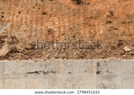 Minimal construction background featuring orange soil occupying most of the frame and concrete texture below. Suitable for graphic design, architecture and engineering concepts.