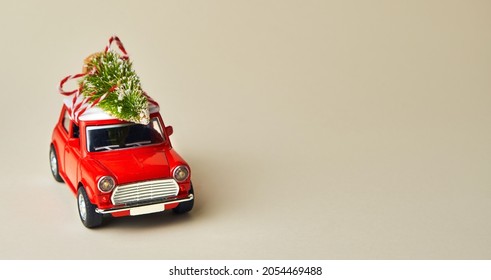 Minimal design for celebrating christmas or new year greeting card. Gift delivery concept. Little red toy car and Christmas tree on a light background - Powered by Shutterstock