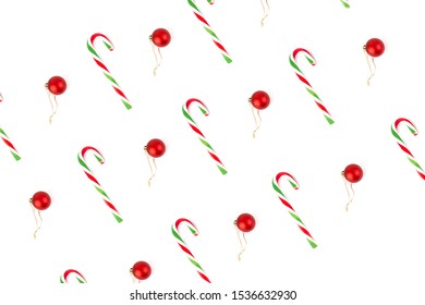 Minimal flat lay design of elements such as red decoration ball, red and green striped sweet candy cane, for Christmas season on white background.