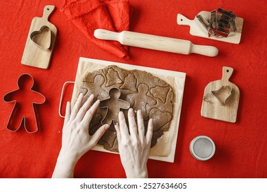 Minimal flat lay style, preparation Cooking ginger cookies on red tablecloth, Top view cooking Christmas and New Year holiday cookies at home, woman hands cutting biscuits, winter seasonal sweet food - Powered by Shutterstock