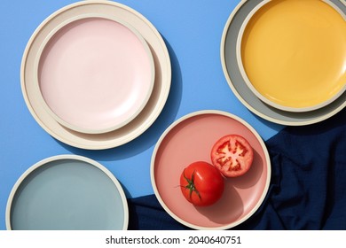 Minimal flatlay of  tomato and slice tomato on colorful plates with linens napkins. Topview. 
