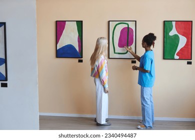 Minimal full length portrait of two teenagers girls discussing modern art in gallery or museum, copy space - Powered by Shutterstock