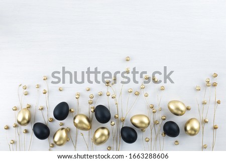 Minimal gold eggs easter concept. Stylish easter golden and black quail eggs with dried golden flax linum on white wooden background. Flat lay trendy easter. Happy easter card with copy space for text