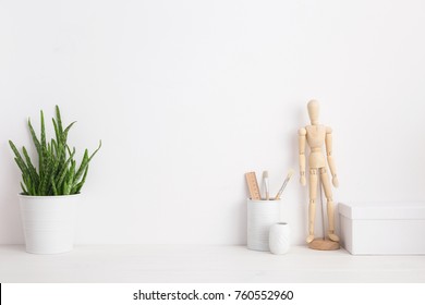 Minimal home decor mock up. Creative desk with wooden manequin, desk objects, office supplies, box and plant on a white background. 