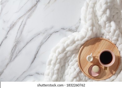 Minimal Home Workspace With Diary, Pen, Cup Of Coffee, Milk, French Macaron And Cozy Snow White Knit Cotton Plaid. Handmade Merino Wool Chunky Knit Warm Blanket. Flat Lay, Top View. Organic Cotton.