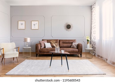 Minimal Interior Design Of Living Room With Brown Leather Couch, Retro Armchair Coffee Table And Golden Decorations, Real Photo