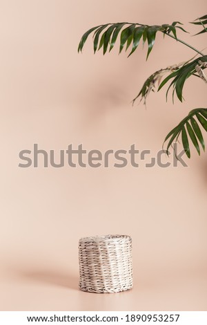 Minimal modern product display on neutral beige background with wicker podium from natural materials decorated palm leaves.  Empty stand on light color backdrop. Copy space.