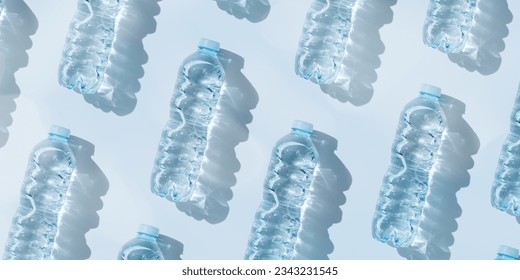 Minimal Pattern from Plastic bottles drinking water at sunlight with shadow on pastel blue, aesthetic top view wide banner. Pollution, environmental protection. Eco trend to reduce disposable plastics
