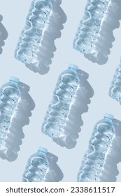 Minimal Pattern from Plastic bottles water at sunlight with shadow on blue, aesthetic top view. Distilled drinking water. Pollution, environmental protection. Eco trend to reduce disposable plastics
