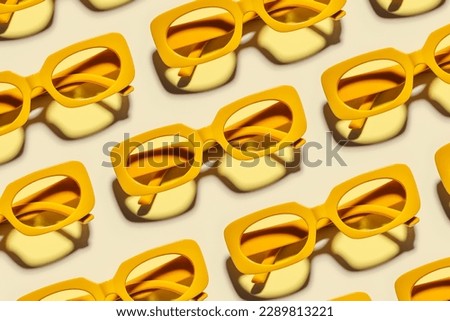 Minimal pattern from yellow eyeglasses on beige background, visual trends summer concept. Top view aesthetic photo, colored sunglasses as creative geometric pattern, monochrome flat lay style glasses