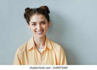 Minimal Portrait Of Cheerful Young Woman With Genuine Smile Looking At Camera Against Blue Wall, Copy Space