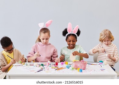 Minimal Portrait Of Diverse Group Of Children Painting Easter Eggs And Wearing Bunny Ears While Enjoying Art And Craft Class In School, Copy Space