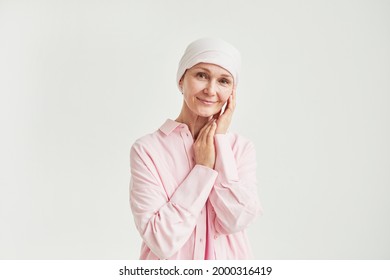 Minimal portrait of elegant mature woman wearing headscarf and looking at camera while standing against white celebrating breast cancer recovery, copy space - Powered by Shutterstock