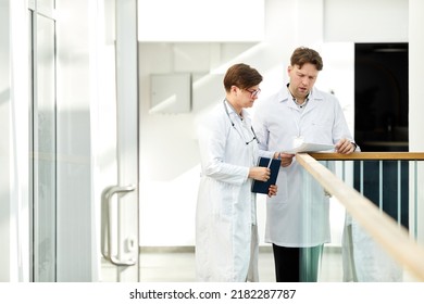 Minimal Portrait Of Two Expert Doctors Discussing Case In Hall Of Modern Clinic In White Tones, Copy Space