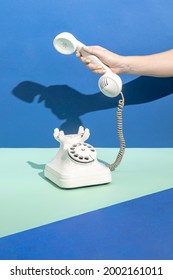 Minimal Retro Office Concept With Hand Answering White Vintage Phone On Green And Blue Background. Retro Futuristic Telephone Call Aesthetic, Promotion, Communication, Advertisement Creative Idea.