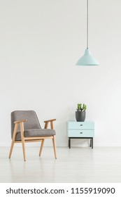 Minimale Raumausstattung mit Retro-Sessel, kleiner Schrank mit Pflanze und Lampe. Ihr Logo hier platzieren