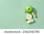 Minimal scene of fresh green apple cut in slices decorated on pastel background. Copy space. Blank space for product promotion. Green Apple (Malus domestica) is really good for skin and hair
