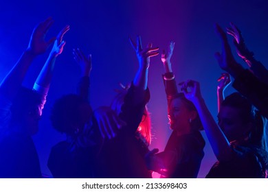 Minimal Shot Of Diverse Crowd Dancing In Club With Hands Up Lit By Neon Lights