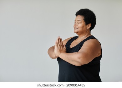 Minimal Side View Portrait Of Black Senior Woman Meditating With Eyes Closed While Doing Yoga Indoors, Copy Space