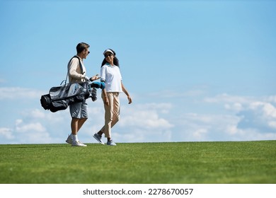 Minimal side view portrait of elegant sporty couple carrying golf bag walking on green field against blue sky, copy space - Powered by Shutterstock