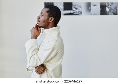 Minimal Side View Portrait Of Handsome Black Man Looking At Images In Photo Gallery And Enjoying Art