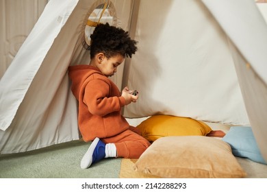 Minimal Side View Portrait Of Little African American Boy Using Smartphone In Play Tent And Wearing Trendy Outfit, Gen Alpha, Copy Space