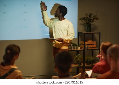 Minimal Side View Portrait Of Young Black Man Giving Presentation By Projector Screen During Business Meeting Or Training Session, Copy Space