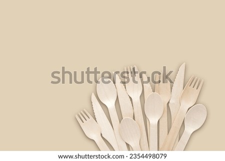 Minimal simplistic biodegradable wooden bamboo single use cutlery on beige background fanned out with copy space