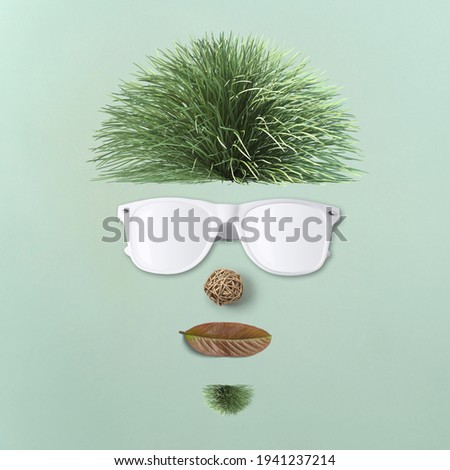 Minimal spring concept. Creative crazy face made of green grass, leaf and sunglasses on pastel blue background. Top view.