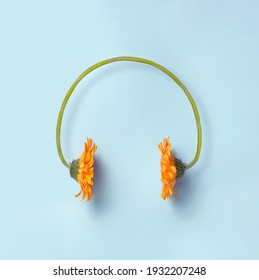 Minimal Spring And Music Concept. Two Orange Daisy Flowers Making A Headset On A Simple Blue Background. Sounds Of Nature. 