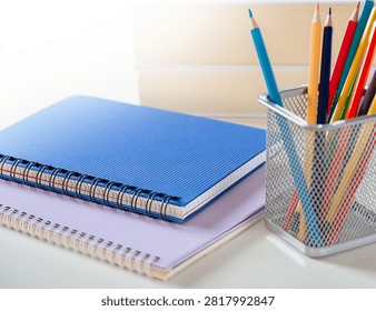Minimal Study Desk Setup with Blue Notebook and Colorful Pencils
A clean and bright workspace featuring a blue spiral notebook, stacked stationery, and a metal pencil holder filled with colorful pencils. The minimalist desk arrangement creates an inspiring atmosphere for studying, writing, creativity, and office work.