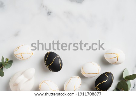 Minimal style Easter eggs, bunny rabbit, eucalyptus leaves on marble table. Happy Easter greeting card template.