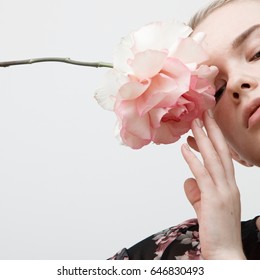 Minimal Style. Minimalist Fashion Photography. Vintage. Glamour. A Girl In A Black Blouse With A Fresh Flower In Her Hands On A White Wall Background