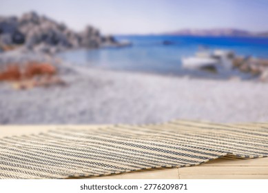 Minimal summer composition featuring clean sandy beach with empty copy space for product placement. In the background, a rocky coastline meets the sea under a bright blue sky, creating a natural and scenic atmosphere. Ideal for advertising, travel promotions, and summer lifestyle concepts.
