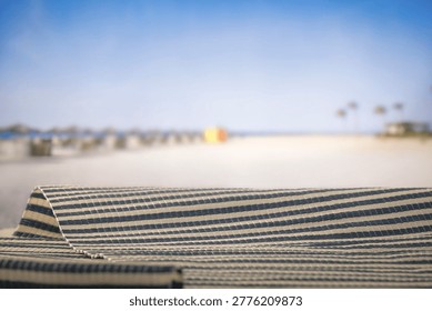 Minimal summer composition featuring clean sandy beach with empty copy space for product placement. In the background, a rocky coastline meets the sea under a bright blue sky, creating a natural and scenic atmosphere. Ideal for advertising, travel promotions, and summer lifestyle concepts.