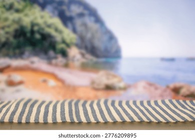Minimal summer composition featuring clean sandy beach with empty copy space for product placement. In the background, a rocky coastline meets the sea under a bright blue sky, creating a natural and scenic atmosphere. Ideal for advertising, travel promotions, and summer lifestyle concepts.