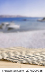 Minimal summer composition featuring clean sandy beach with empty copy space for product placement. In the background, a rocky coastline meets the sea under a bright blue sky, creating a natural and scenic atmosphere. Ideal for advertising, travel promotions, and summer lifestyle concepts.