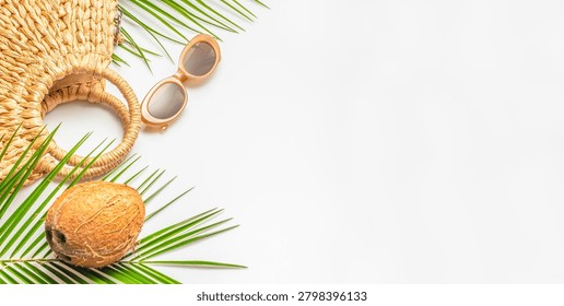Minimal summer flat lay featuring a woven straw bag, sunglasses, coconut and tropical palm leaves on a white background. copy space. Vacation beach holiday concept.