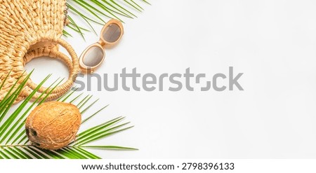 Minimal summer flat lay featuring a woven straw bag, sunglasses, coconut and tropical palm leaves on a white background. copy space. Vacation beach holiday concept.