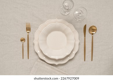 Minimal table setting in beige color with gold cutlery. Top view, copy space. - Powered by Shutterstock