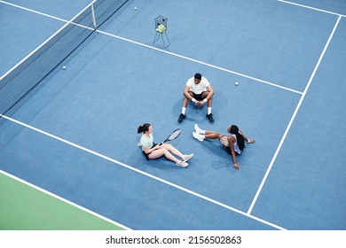 Minimal top view at group of people relaxing at indoor tennis court and sitting on graphic blue flooring, copy space - Powered by Shutterstock