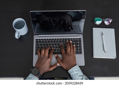 Minimal Top View Of Unrecognizable African-American Man Using Laptop While Working At Black Desk Background, Focus On Hands At Keyboard, Copy Space