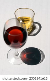 Minimal Visual Glass of Red Wine and Whiskey on White Background Table With Long Shadows Under Sunray